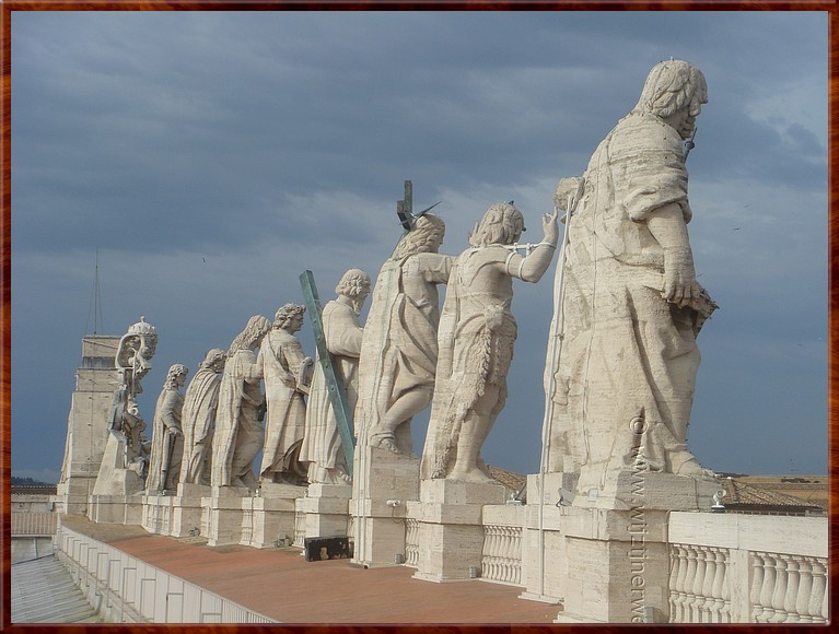 088 Vaticaan - St Pieter Basiliek - De apostelen op de voorgevel overzien de drukte op het Plein.jpg